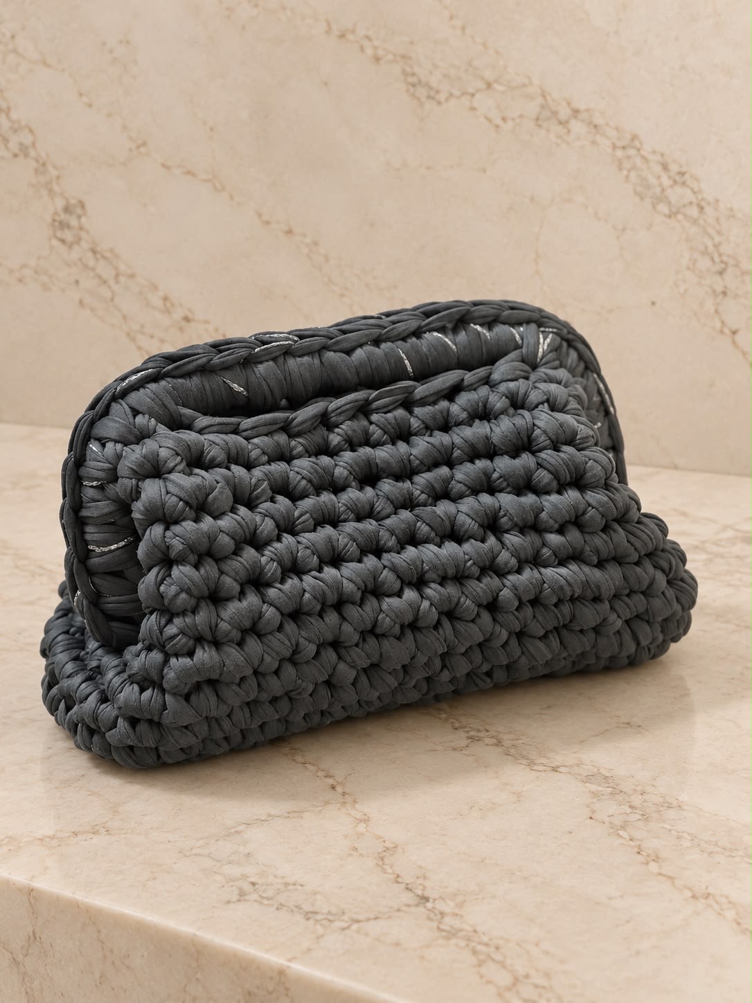 Pochette Kikka all'uncinetto in fettuccia grigia su sfondo marmo